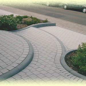 Elegante Gestaltung mit Radien-       Bordsteinen rinnit Basalt und Silitonpflaster Granit